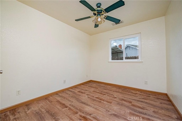 empty room featuring visible vents, a ceiling fan, baseboards, and wood finished floors