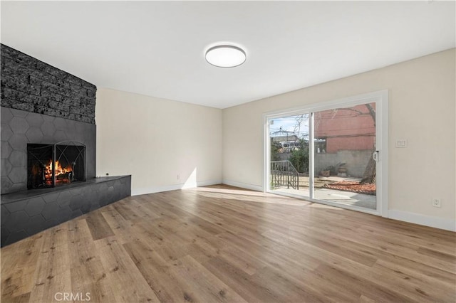 unfurnished living room featuring baseboards, wood finished floors, and a fireplace