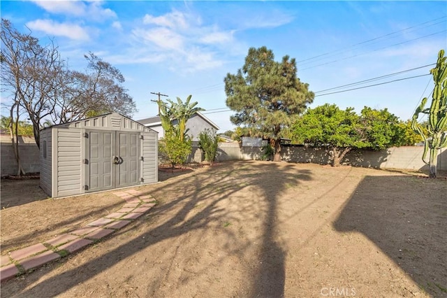 view of yard featuring a storage unit, a fenced backyard, and an outdoor structure