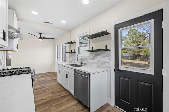 kitchen with a sink, under cabinet range hood, white cabinetry, dishwasher, and ceiling fan