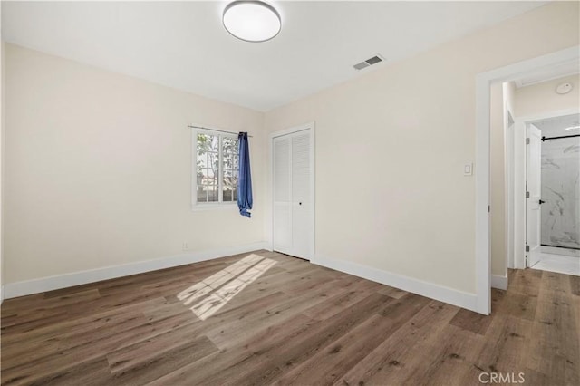 empty room featuring visible vents, wood finished floors, and baseboards