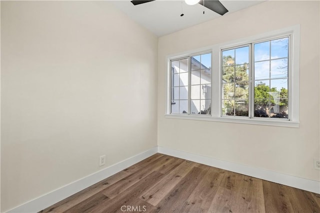 spare room featuring wood finished floors, plenty of natural light, a ceiling fan, and baseboards