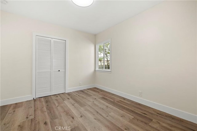 unfurnished bedroom featuring a closet, light wood finished floors, and baseboards