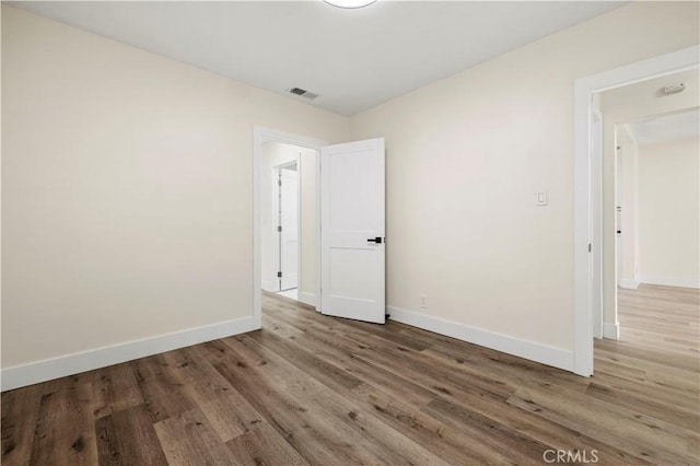 spare room featuring visible vents, baseboards, and wood finished floors