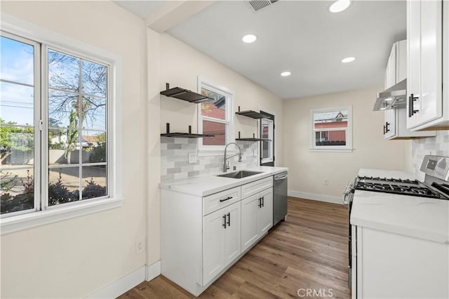 kitchen with baseboards, open shelves, light wood-style flooring, a sink, and appliances with stainless steel finishes