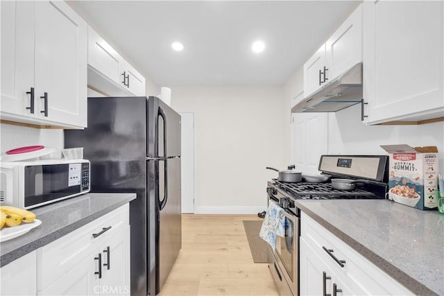 kitchen with white microwave, stainless steel range with gas cooktop, freestanding refrigerator, white cabinets, and under cabinet range hood