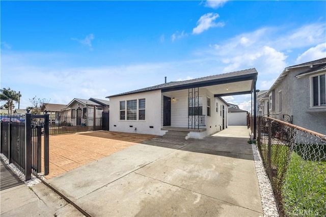 view of front of house with concrete driveway, fence, an outdoor structure, and stucco siding