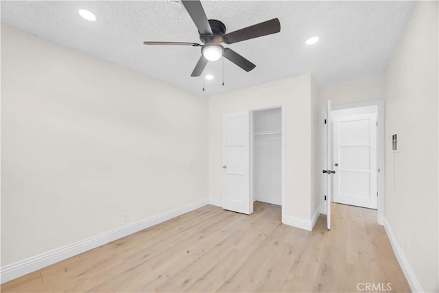 unfurnished bedroom featuring light wood-style floors, baseboards, and a textured ceiling