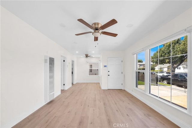 unfurnished living room featuring light wood-type flooring, baseboards, and a ceiling fan