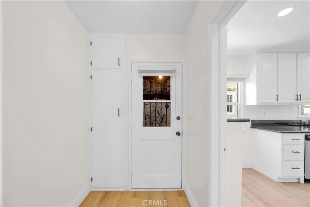 doorway with light wood finished floors, recessed lighting, and baseboards