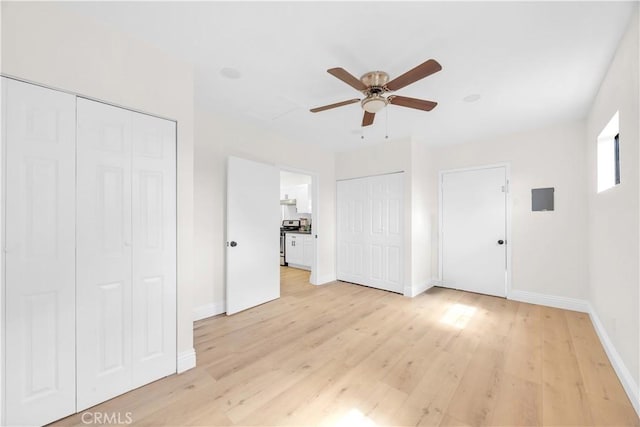 unfurnished bedroom with ceiling fan, baseboards, light wood-type flooring, and multiple closets