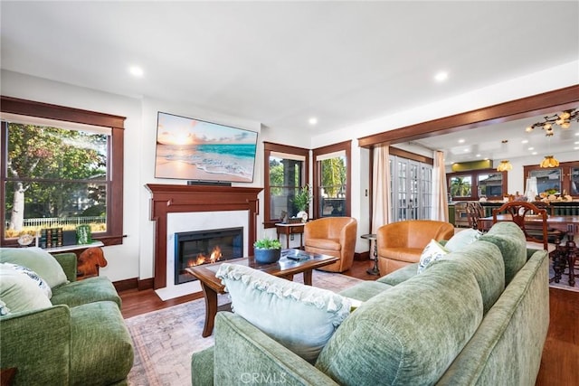 living room featuring a fireplace with flush hearth, plenty of natural light, and wood finished floors