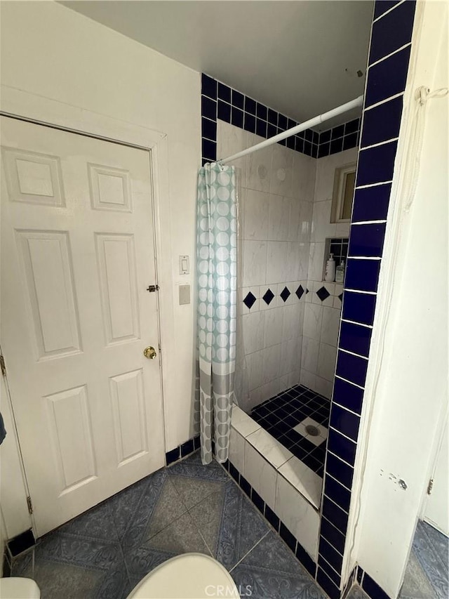 bathroom featuring tile patterned flooring, a stall shower, and toilet