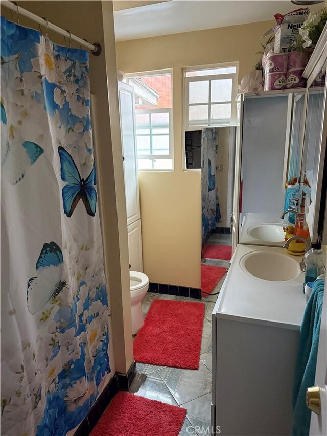 bathroom with toilet, tile patterned floors, plenty of natural light, and vanity