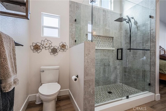 full bath with a shower stall, wood finished floors, and a wealth of natural light