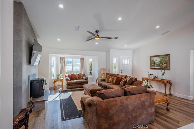 living room featuring lofted ceiling, wood finished floors, visible vents, and ceiling fan