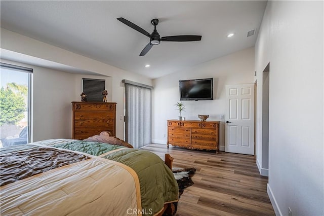 bedroom with vaulted ceiling, wood finished floors, visible vents, and baseboards