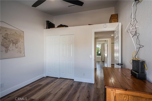 unfurnished bedroom with dark wood-type flooring, visible vents, baseboards, and a closet