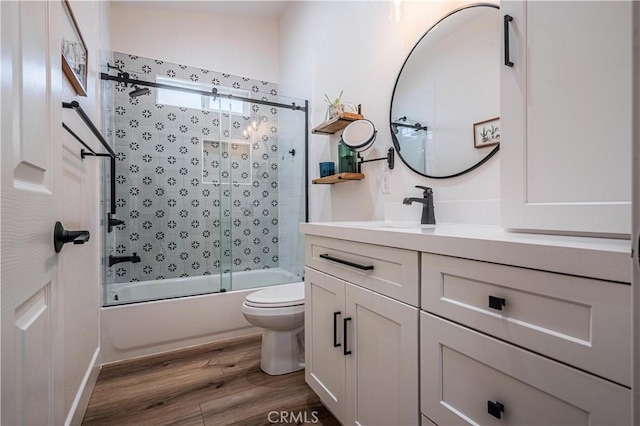 full bathroom with enclosed tub / shower combo, toilet, wood finished floors, and vanity