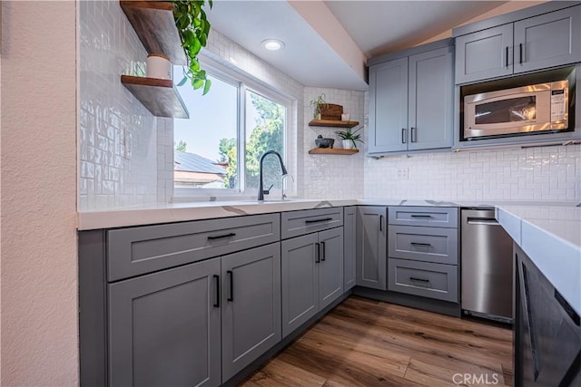 kitchen featuring dark wood-style floors, open shelves, gray cabinets, light countertops, and stainless steel microwave