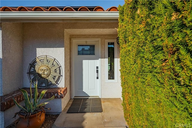 entrance to property with stucco siding and a tiled roof