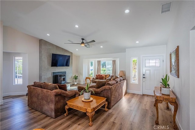 living room featuring visible vents, recessed lighting, a large fireplace, light wood-style floors, and lofted ceiling