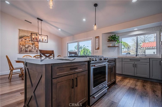 kitchen featuring dark wood-style floors, visible vents, a kitchen island, lofted ceiling, and high end stove