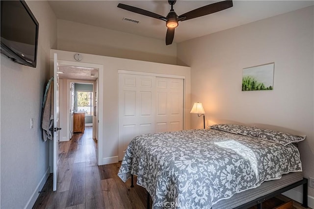 bedroom with visible vents, a ceiling fan, wood finished floors, a closet, and baseboards