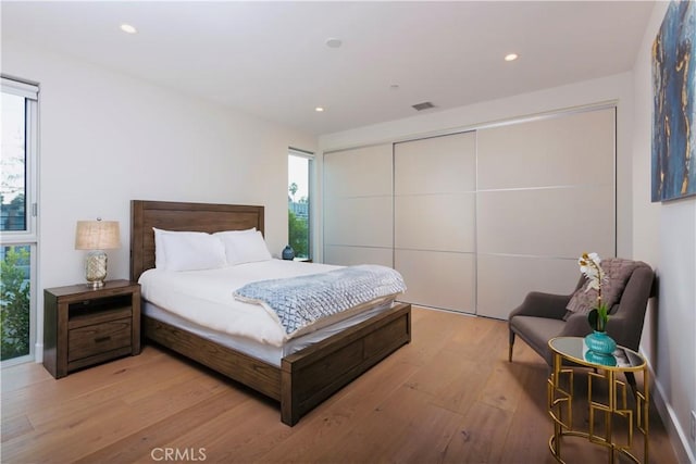 bedroom with recessed lighting, light wood-type flooring, visible vents, and a closet