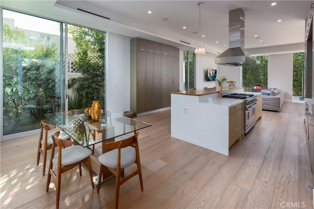 kitchen with recessed lighting, light wood-style floors, stainless steel stove, and island range hood