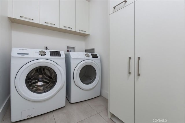 washroom featuring light tile patterned flooring, cabinet space, and washer and clothes dryer