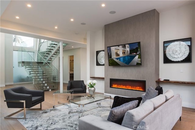 living area featuring baseboards, stairs, recessed lighting, a fireplace, and wood finished floors