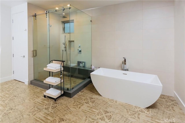 bathroom with tile walls, a freestanding tub, and a stall shower