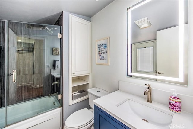 full bath with visible vents, toilet, vanity, and shower / bath combination with glass door