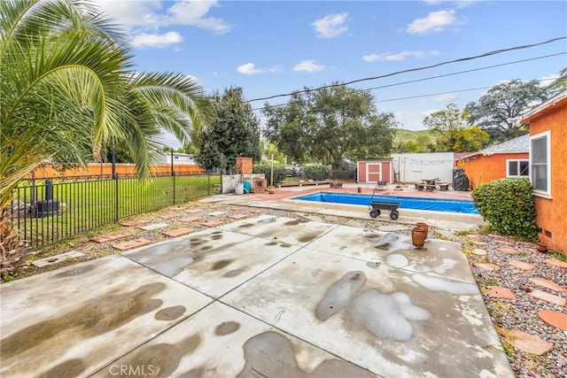 view of swimming pool with a storage unit, a fenced backyard, an outdoor structure, a fenced in pool, and a patio area