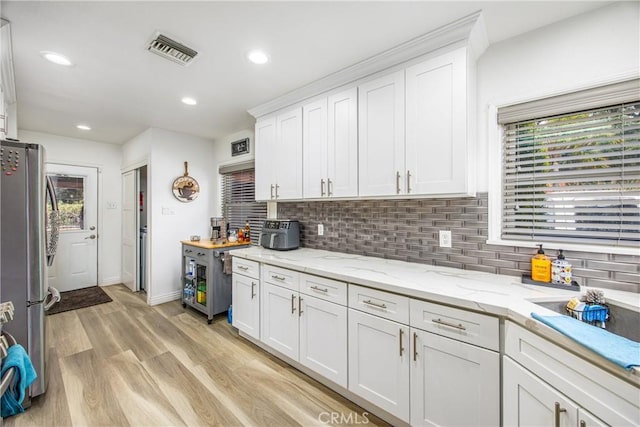 kitchen featuring light wood finished floors, visible vents, white cabinets, and freestanding refrigerator