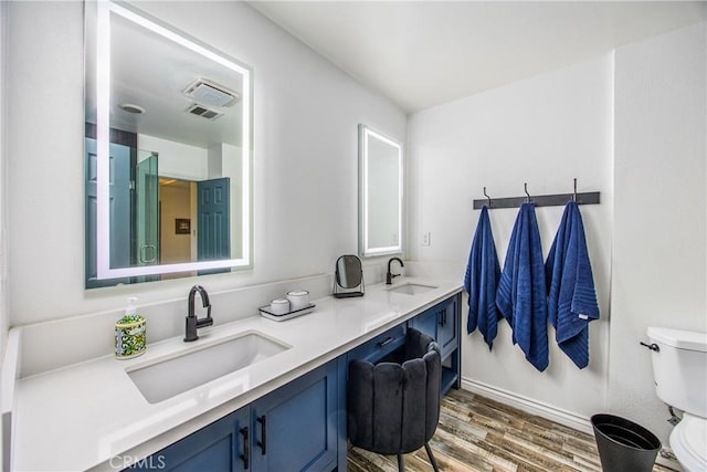 full bathroom with double vanity, toilet, wood finished floors, and a sink