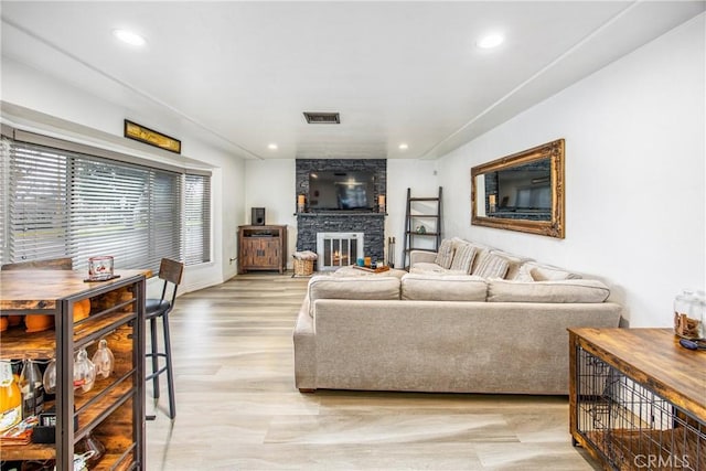 living room with recessed lighting, visible vents, light wood-style floors, and a fireplace