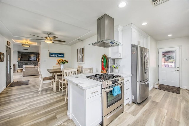 kitchen with range hood, light wood-style flooring, light stone countertops, and appliances with stainless steel finishes