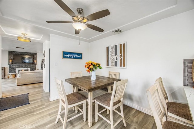 dining room featuring a ceiling fan, visible vents, light wood finished floors, and baseboards