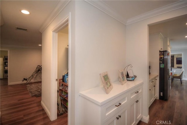 hall with dark wood-style floors, baseboards, visible vents, ornamental molding, and recessed lighting
