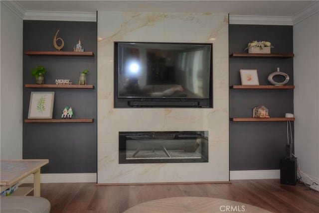 living area featuring a fireplace, ornamental molding, built in shelves, and wood finished floors