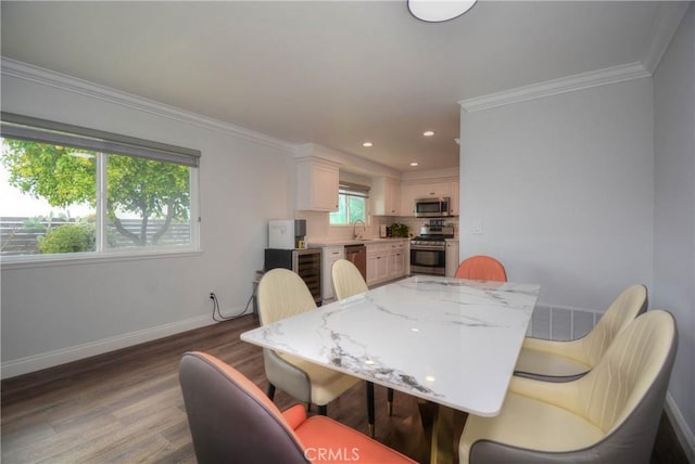 dining room with baseboards, ornamental molding, wood finished floors, wine cooler, and recessed lighting