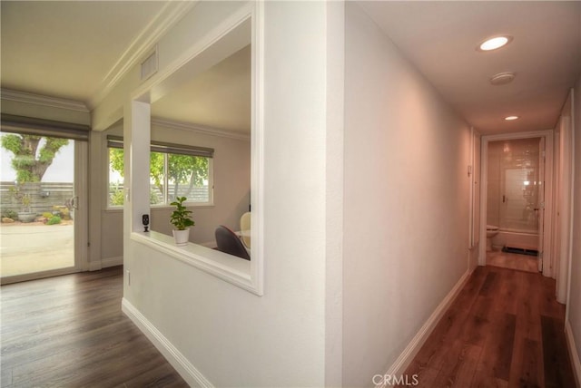 hall with dark wood finished floors, baseboards, visible vents, ornamental molding, and recessed lighting