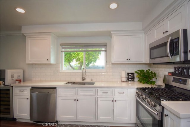kitchen featuring light countertops, wine cooler, appliances with stainless steel finishes, white cabinetry, and a sink