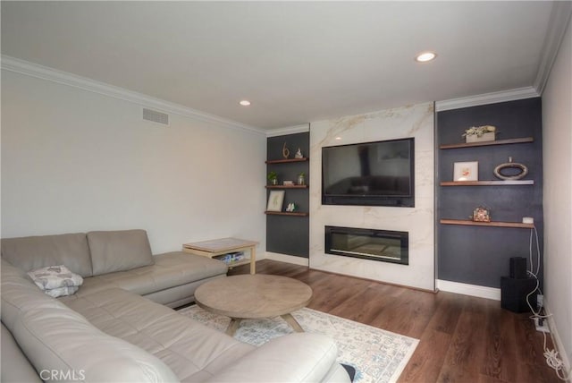 living room featuring wood finished floors, ornamental molding, built in shelves, and visible vents