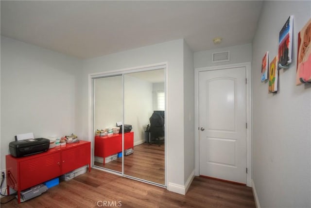 bedroom with baseboards, visible vents, a closet, and wood finished floors