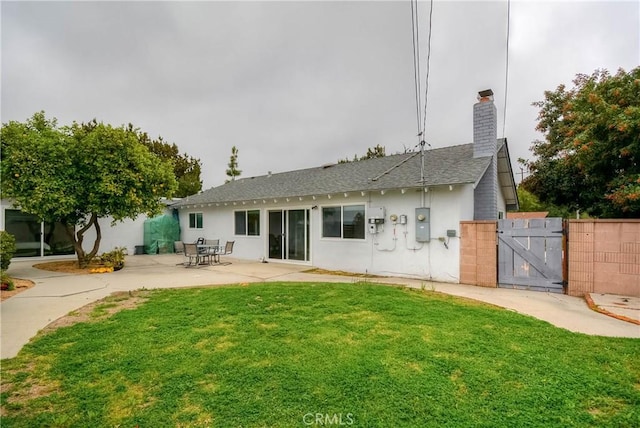 rear view of house featuring a gate, fence, stucco siding, a yard, and a patio area