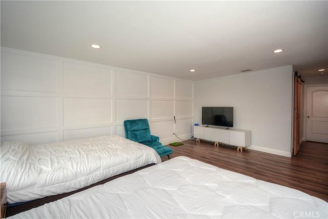 bedroom with recessed lighting, baseboards, visible vents, a decorative wall, and wood finished floors