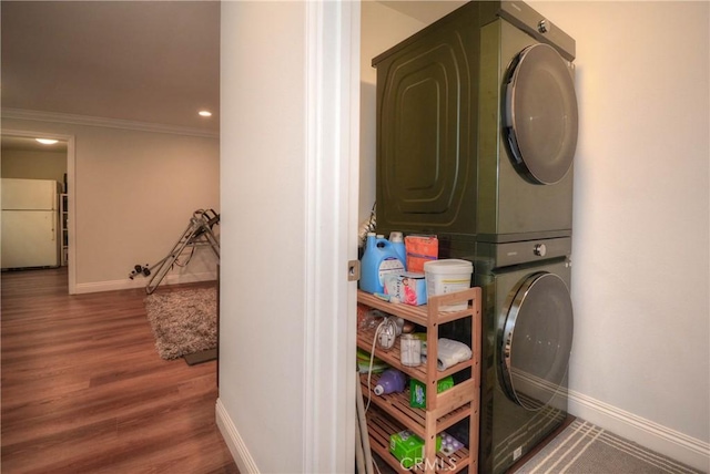 washroom featuring wood finished floors, baseboards, laundry area, and stacked washer / drying machine